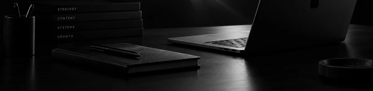 Black notebooks, a pen and a laptop on a quiet desk